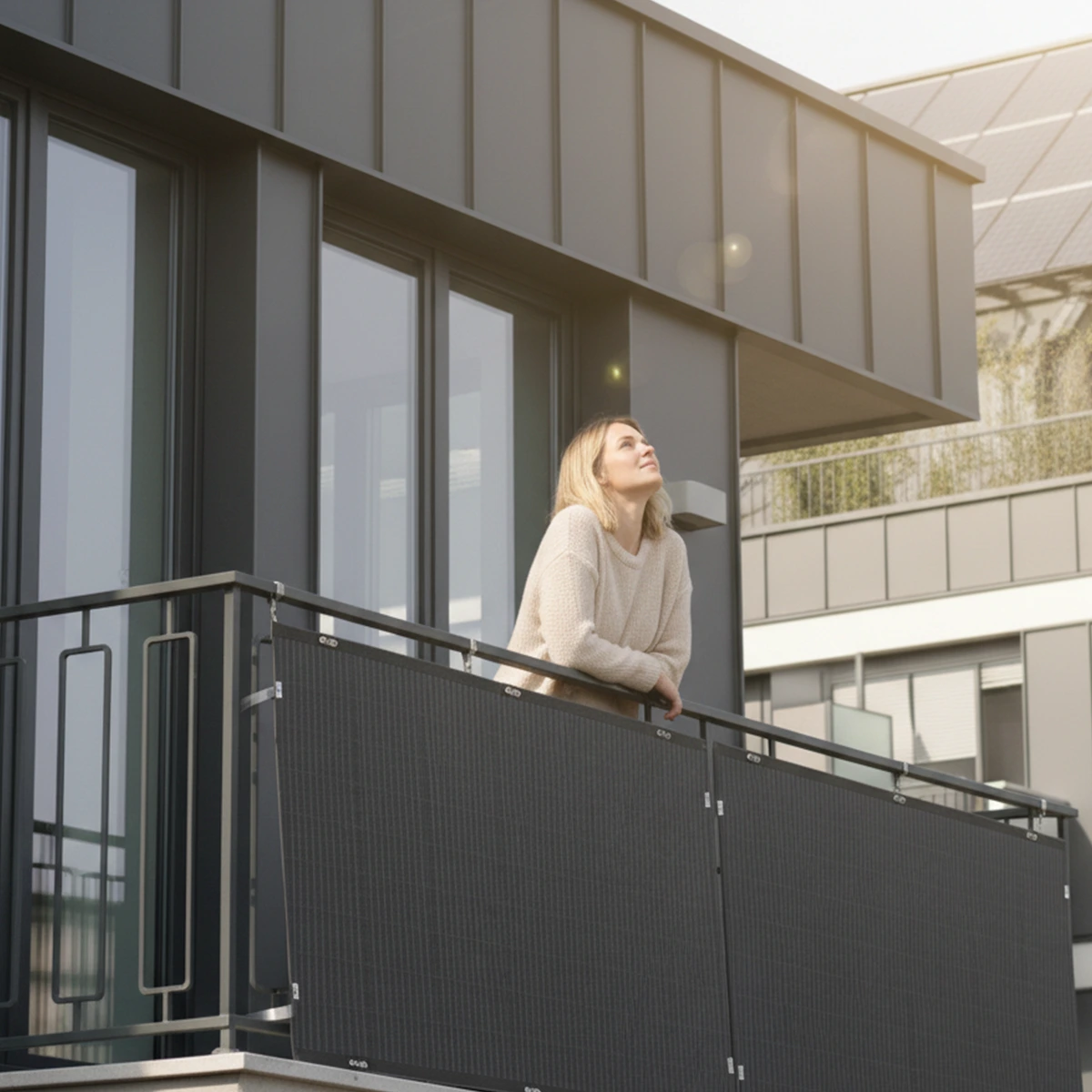 una donna guarda i pannelli solari flessibili installati sul balcone di casa